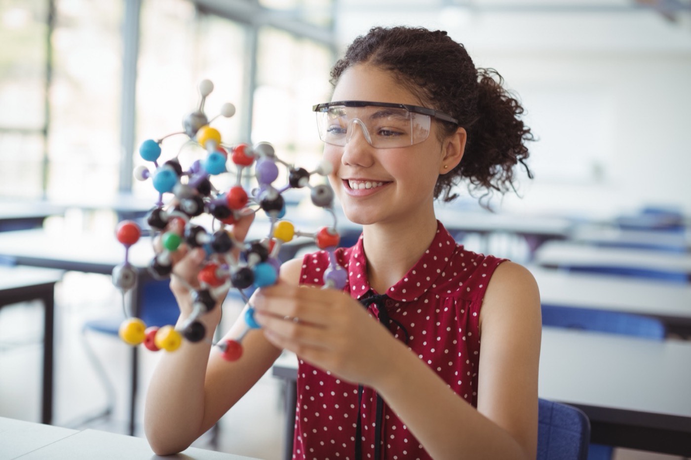 Estudiante sonriendo mientras explora un modelo molecular en clase
